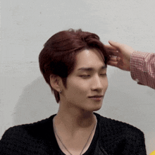 a person touching a young man 's head with their hand