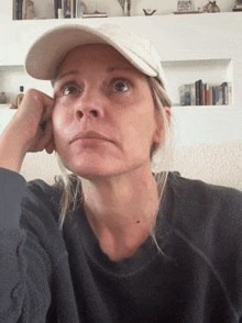a woman wearing a white hat and a black sweater looks tired