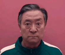 an older man in a green jacket is making a funny face .