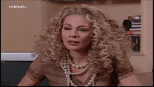 a woman with curly hair and a pearl necklace is on a television screen with mega written on it