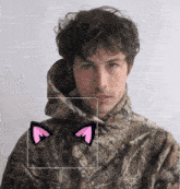a man in a camo hoodie has a pair of pink cat ears on his face