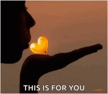 a woman is blowing a heart shaped balloon in the air .
