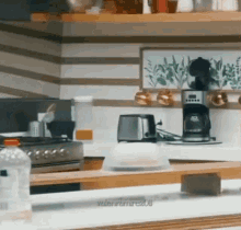 a kitchen with a stove , toaster , coffee maker and a bottle of water on the counter .