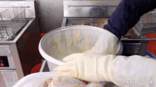 a person wearing gloves is putting chicken into a bucket that says made in animatica on it