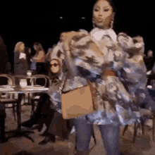 a woman is standing in front of a crowd of people holding a purse .
