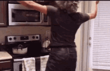 a woman in a black shirt is dancing in a kitchen .
