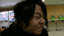 a man is making a funny face in front of a vending machine that says coca cola