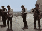 a group of men are standing on a dirt road