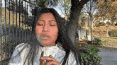 a woman is smoking a cigar in front of a tree .
