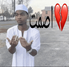 a man in a white shirt prays with a broken heart behind him