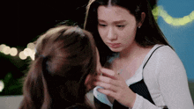two women are touching each other 's faces and one of them is crying
