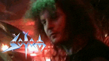a man playing drums in front of a sign that says ' sodom '