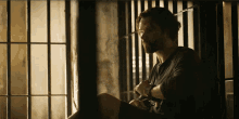 a man in a prison cell looking out the window