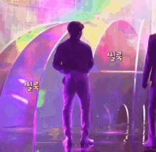 a man is standing on a stage in front of a rainbow colored archway .