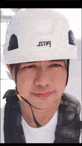a man wearing a white petzl helmet is smiling