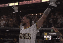 a man in a padres jersey holds his arm up in the air
