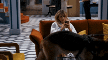 a woman sits on a couch looking at her cell phone