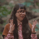 a woman wearing glasses is making a funny face with her hands up
