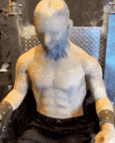 a statue of a shirtless man with a beard sits in a chair