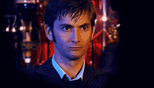 a man in a suit and tie looks at the camera with a serious look on his face