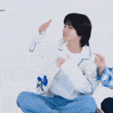 a person wearing a white shirt with blue flowers on it is sitting on the floor