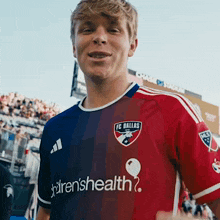 a man wearing a dallas fc jersey with children 's health written on the front