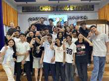 a group of young people posing for a picture in front of a banner that says jesus christ king eternal