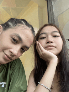 two girls are posing for a picture with one wearing a bracelet