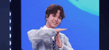 a young man in a denim jacket and tie is making a peace sign