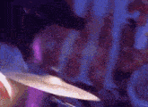 a person is playing a drum set in a dark room with purple lights .