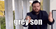 a man with a beard is making a gesture with his hands and the words `` grey son '' written on it .