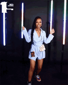 a woman in a blue dress dancing in front of a bet awards logo