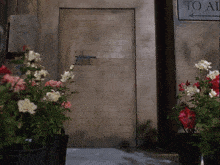 a sign that says to all is next to a door with flowers in front of it