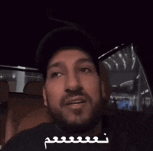 a man with a beard is wearing a black hat and a black shirt
