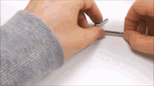 a person wearing a grey sweater is holding a metal object in their hand