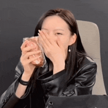 a woman covering her face with her hand while holding a sandwich