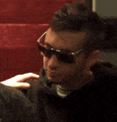 a close up of a man wearing sunglasses and a black sweatshirt