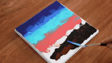 a person is using a spatula to paint a painting on a canvas