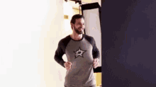 a man with a beard is wearing a t-shirt with a star on it and is running .