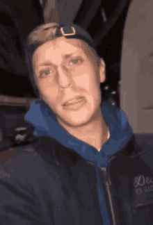a man wearing a blue hoodie and a black jacket that says emporio armani on it
