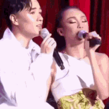 a man and a woman are singing into microphones on stage .