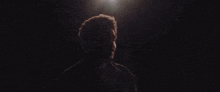 a man with a beard is standing in a dark room looking up