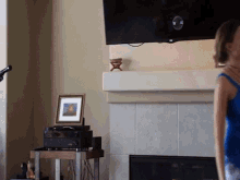 a woman stands in front of a fireplace in front of a tv