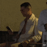 a man sitting in a chair looking at his cell phone