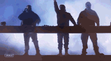 three men are standing in front of a stage with a sign that says campbella on it