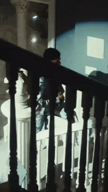 a person is standing on a staircase with a shadow on the railing .