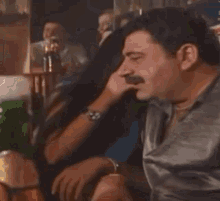 a man is drinking from a green bottle in a restaurant .