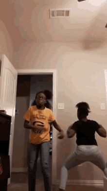 a girl in a yellow shirt with the letter g on it is dancing with another girl