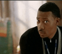 a man wearing a lanyard around his neck is making a funny face .