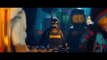 a lego batman standing next to a lego ninjago character